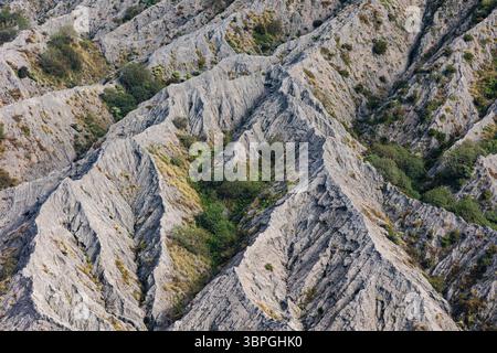 Der Blick auf raues, trockenes Gelände mit tiefen Schluchten und karger Vegetation schafft eine strukturierte Landschaft, Mount Bromo, Ost-Java, Indonesien. Stockfoto
