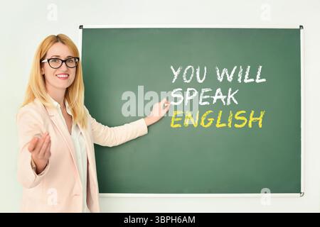 Lehrer, der auf Text zeigt, sprechen Sie Englisch auf grüner Tafel. Sprachkurs Stockfoto