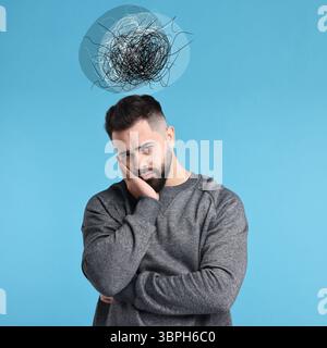 Besorgter Mann auf hellblauem Hintergrund. Verwirrte Gedanken wie Kritzeleien über seinem Kopf. Stress, Angst, Depression Stockfoto