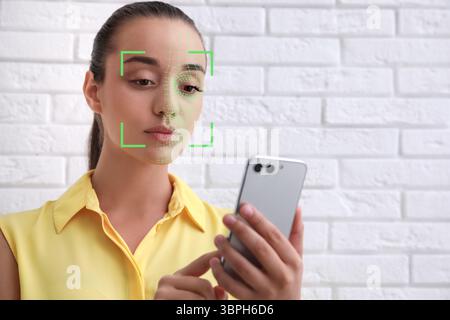 Frau entsperrt ihr Smartphone mit der Gesichtserkennungs-App in Innenräumen. Biometrische Verifizierung Stockfoto