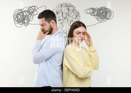 Besorgter Mann und Frau auf weißem Hintergrund. Verwirrte Gedanken als Kritzeleien über ihren Köpfen. Missverständnis, Stress, Angst Stockfoto