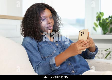 Frau entsperrt ihr Smartphone mit der Gesichtserkennungs-App zu Hause. Biometrische Verifizierung Stockfoto
