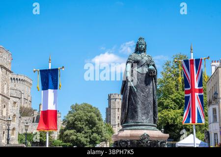 Französischer Staatsbesuch, Windsor, Berkshire. Vereinigtes Königreich 8 Juli Französische Flagge und Vereinigtes Königreich Union Flagge auf Bannern mit Statue der Königin Victoria am Eingang von Windsor Castle Street ,'Emmanuel Macron, der Präsident Frankreichs, zusammen mit seiner Frau wurde Brigitte heute von König Charles bei einem Staatsbesuch empfangen. er wurde mit einer Parade um Windsor in offenen Kutschen von den Royal Mews begrüßt, bevor er die Tore von Windsor Castle betrat, um weitere Veranstaltungen und Gespräche mit dem König während ihres Aufenthalts auf der Burg zu führen.“ Gary Blake /Alamy Live News Stockfoto