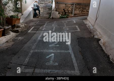 Frau neben Hopscotch zeichnet in der Urban Athens Alley Stockfoto