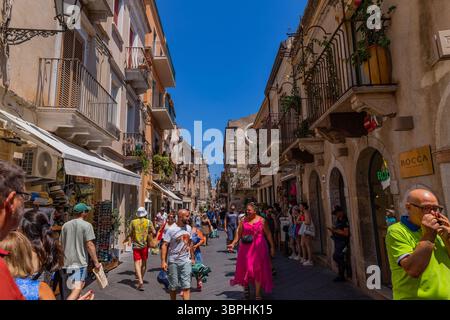 Venedig, Italien - 23. Juli 2024: Historische Straße in der Altstadt von Taormina, Sizilien. Touristen, die einen sonnigen mediterranen Tag genießen. Stockfoto