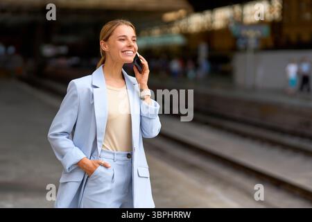 Eine selbstbewusste Frau redet gerne am Telefon, während sie am Bahnhof steht Stockfoto