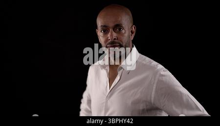 Porträt eines seriösen afroamerikanischen Geschäftsmannes, der ein weißes Hemd auf schwarzem Hintergrund trägt Stockfoto