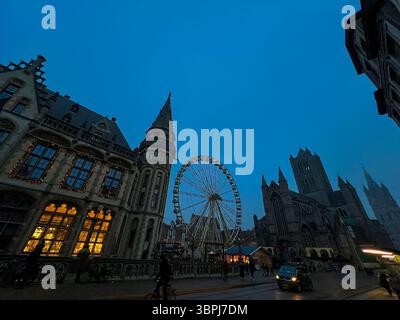 Festliches Riesenrad hinter der Kathedrale von Gent mit weihnachtsmarkt-Glühen Stockfoto