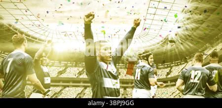 Multirassische männliche Spieler mit erhobenen Armen stehend mit der Mannschaft im Stadion Stockfoto