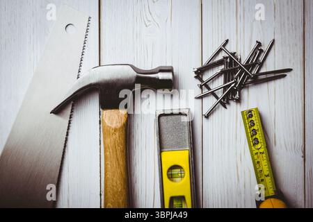 Die flache Ausführung zeigt Schreinerwerkzeuge, Hammer, Säge, Nivellierung, Nägel und Maßband auf Holzdiele Stockfoto