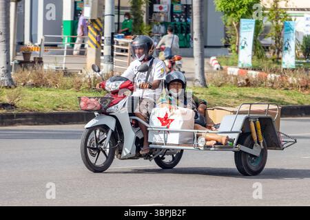 RATCHABURI, THAILAND, 18. Oktober 2022, Mann, der ein Motorrad fährt, mit einer Frau, die mit einer Ladung im Beiwagen sitzt Stockfoto
