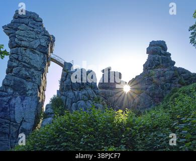 Die Morgensonne scheint durch eine Öffnung in den Externsteinen. Die Externsteine, eine rund 40 Meter hohe Sandsteinformation in der Teutoburg Stockfoto