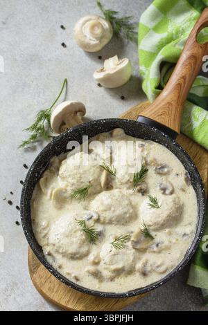 Hausgemachte Fleischbällchen in Sauerrahmsauce mit Pilzen in einer Pfanne auf Stein- oder Schiefertisch. Kopierbereich Stockfoto