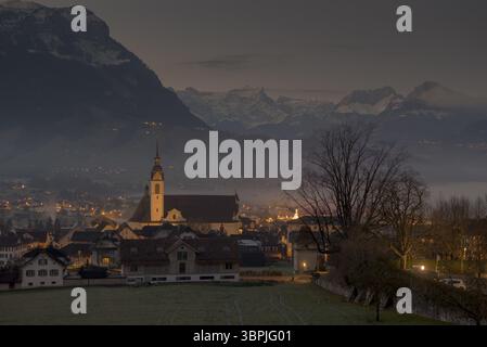 Eine Kirche im Dorf Schwyz in der Schweiz bei Dämmerung mit Nebel und den Bergen der Alpen, Schwyz, Schweiz, Europa Stockfoto
