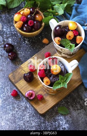 Sommerfrühstück oder Dessert. Schokoladen-Cupcake in einem Becher wird mit frischen Sommerbeeren Himbeeren und Kirschen serviert. Kopierbereich Stockfoto