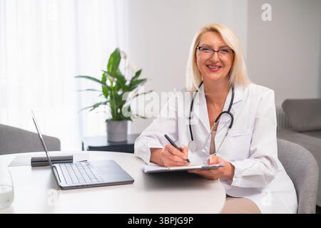 Porträt eines lächelnden Hausarztes im weißen Mantel und Stethoskop besuchen Patienten zu Hause. Stockfoto