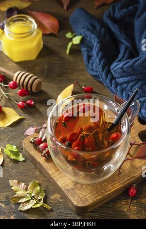 Gesundes Wintervitamingetränk. Heißer Hagebuttentee mit Honig und getrockneten Früchten auf einem Holztisch Stockfoto