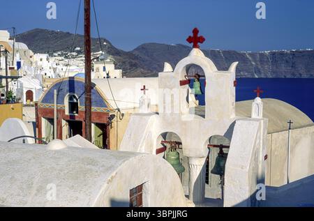 Weiß getönter Glockenturm einer kleinen Kapelle und Häuser in Oia am Rande des Vulkankraters von San Turin, einer Insel der griechischen Kykladen zu ostern Stockfoto