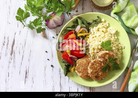 Gesunde vegane Lebensmittel, Keto- oder Paläodiäten. Hausgemachte rote Fischschnitzel mit Bulgur und frischem Gemüsesalat auf einem Holztisch. Draufsicht flach lag hinten Stockfoto