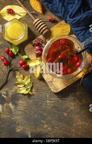 Gesundes Wintervitamingetränk. Heißer Hagebuttentee mit Honig und getrockneten Früchten auf einem Holztisch. Draufsicht flacher Hintergrund. Kopierbereich Stockfoto