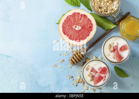 Veganes gesundes Frühstück. Müsli mit griechischem Joghurt, Honig und Grapefruit im Glas. Draufsicht flacher Hintergrund. Kopierbereich Stockfoto