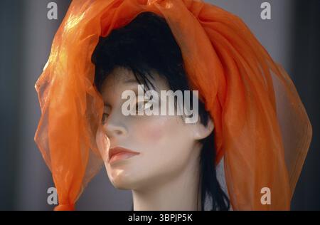 Dekorierte Schaufensterpuppe mit orangefarbenem Kopfschmuck im Hintergrund Stockfoto