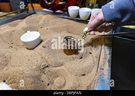 Türkischer Kaffee im Sand zubereitet, türkischer Kaffee vom Straßenverkäufer zubereitet Stockfoto