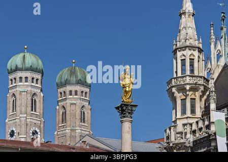 Die vergoldete Marienstatue mit Jesus im Arm auf der Mariensäule am Marienplatz im historischen Zentrum Münchens, eingerahmt von den beiden Türmen der Stadt Stockfoto