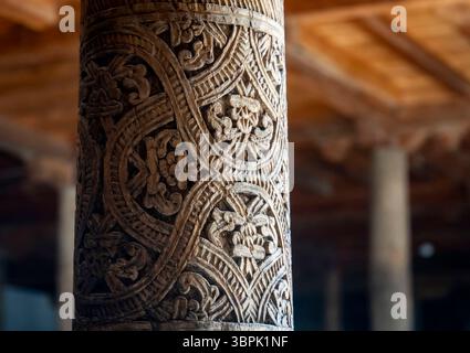 Nahaufnahme einer aufwändig geschnitzten Holzsäule mit Blumenmustern und wirbelnden Designs, die traditionelle Handwerkskunst in einem historischen s zeigt Stockfoto