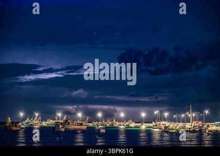 Wenn der Himmel mit Donner leuchtet und Fischerboote ruhig im Hafen ruhen Stockfoto