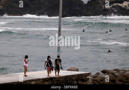 Juni 2020, Lima, Peru: Besucher mit Gesichtsmasken spazieren während des anhaltenden COVID-19-Lockdowns am Strand von San Bartolo (Bild: © Mariana Bazo/ZUMA Wire) Stockfoto