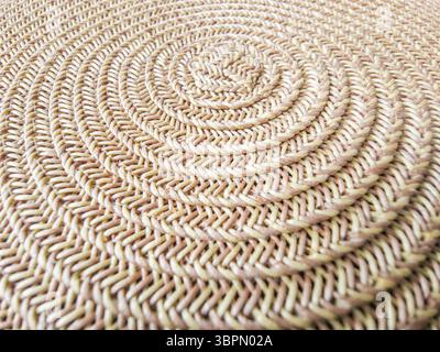 Nahaufnahme einer gewebten runden Matte aus natürlichen Materialien mit detailliertem Spiralmuster. Es ist ideal für die Bereicherung mit ITS Stockfoto
