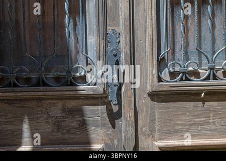 Eine Nahaufnahme einer abgenutzten Holztür im Schloss Rhodos unterstreicht die traditionelle Handwerkskunst und den historischen Charme mit ihren kunstvollen schmiedeeisernen Designs, Stockfoto