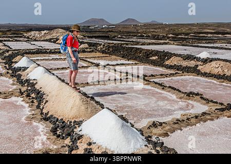 Person mit Salzhaufen, die auf den Salinen, Salinas de los Agujeros, Los Cocoteros, Lanzarote, Kanarischen Inseln, Spanien trocknen Stockfoto