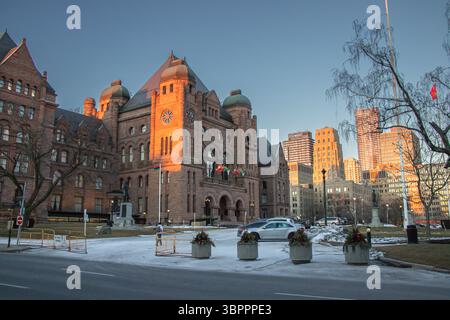 Historisches Ontario Legislative Building in Downtown Toronto, beleuchtet durch warmes Sonnenuntergangslicht an einem kalten Winterabend mit Schneefelken. Stockfoto