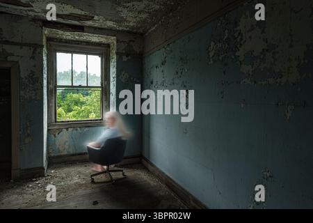 Gruseliger weiblicher Geist in einem verlassenen psychiatrischen Krankenhaus, der über ihre Schulter schaut, Indiana USA Stockfoto