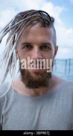 Ein stilvoller Mann mit Dreadlocks, der den Strand an einem wunderschönen Tag voller Abenteuer genießt Stockfoto