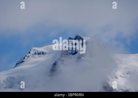 Ein fesselnder Blick auf den Svinafellsjokull-Gletscher, wo sich majestätische Gipfel durch eine Wolkendecke stechen. Diese atemberaubende isländische Landschaft zeigt die Schönheit der Natur in einer anderen Welt. Stockfoto