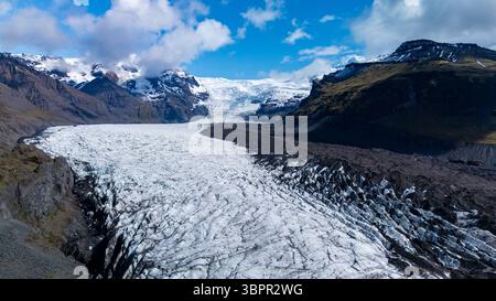 Genießen Sie die atemberaubende Aussicht auf den Svinafellsjokull-Gletscher, wo Gletschereis auf zerklüftete Berge unter lebendigem Himmel trifft. Diese atemberaubende Landschaft fängt das Wesen der natürlichen Schönheit Islands ein. Stockfoto