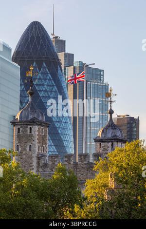 London, UK - 29. April 2025: Die Union-Flagge, die stolz auf dem White Tower of the Tower of London mit den Hochhäusern der City of Lon weht Stockfoto