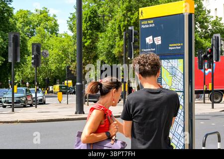 London, England, Großbritannien - 4. Juli 2025: Zwei Personen, die eine Touristeninformationskarte an der Ecke Oxford Street im Zentrum von London überprüfen Stockfoto