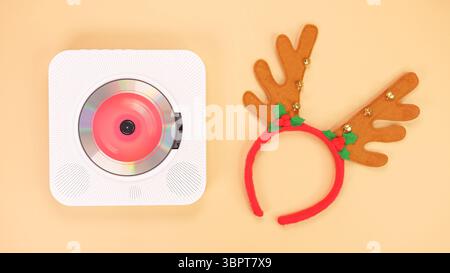 Die Abbildung zeigt einen weißen tragbaren CD-Player mit roten Kopfhörern auf beigefarbenem Hintergrund. Auf der Vorderseite des CD-Players leuchtet eine rote Anzeige, die Kopfhörer A Stockfoto