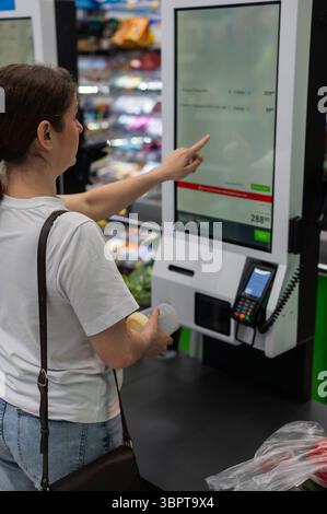 Eine Frau scannt Artikel an einer Selbstkasse. Stockfoto