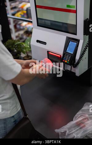Eine Frau scannt Artikel an einer Selbstkasse. Stockfoto