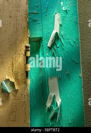 Detail des Türscharniers mit farbenfroher abblätternder Farbe und dramatischem Licht, Indiana USA Stockfoto
