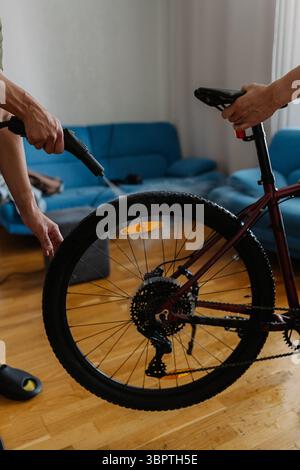 Zwei Personen reinigen das Fahrrad mit Dampfreiniger, entfernen Schmutz und Schmutz in gemütlicher Wohnumgebung und gewährleisten eine gründliche Wartung und Hygiene Stockfoto