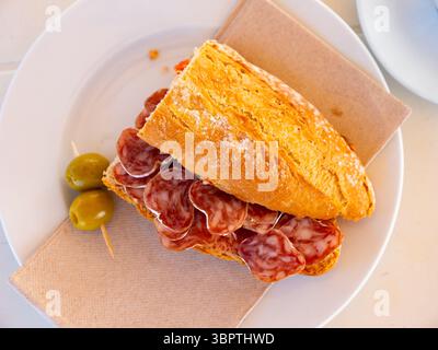 Spanisches Frühstück: Geräuchertes Würstchen-Fuet-Sandwich und Oliven in der Nähe Stockfoto