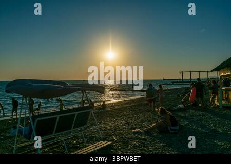 Sotschi, Russland - 5. Juli 2022: Touristen entspannen sich am Sommerstrand im Sonnenuntergang. Sommerurlaub auf dem Meer. Stockfoto