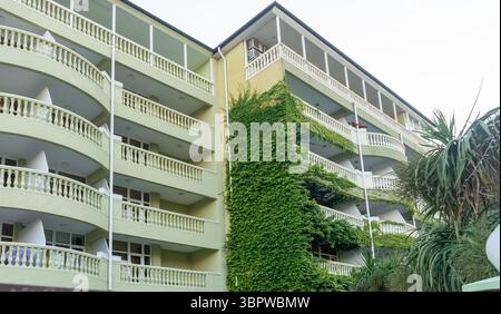 Fassade des Hotelgebäudes mit Balkonen mit einzelnen Zimmern. Grüne Wand des Hotelgebäudes. Stockfoto