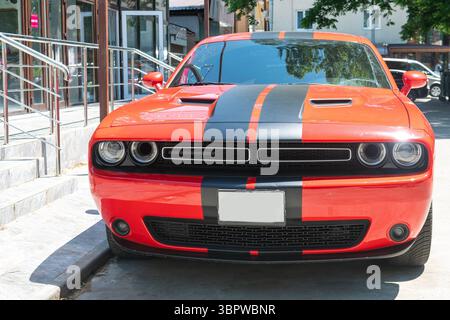 Sotschi, Russland - 05. Juli 2022: Sportwagen in Orange mit schwarzen Streifen an einem sonnigen Tag. Sportwagen parkt am Bordstein. Stockfoto